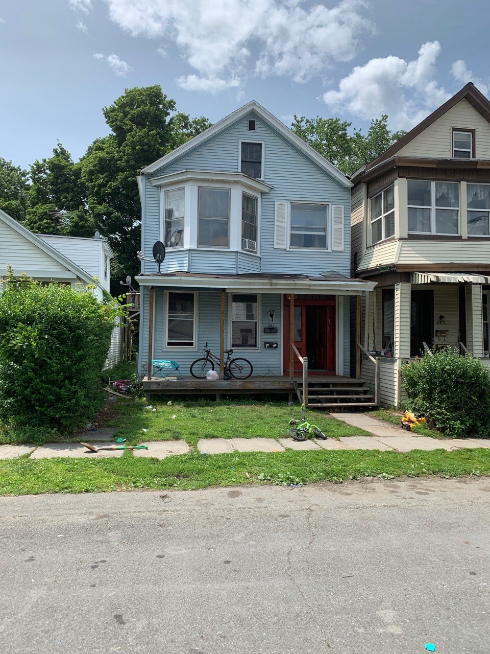 Light blue two-story house with bike on porch we purchased